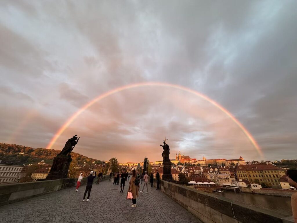 View of Charles Bridge in Prague with a rainbow over the river